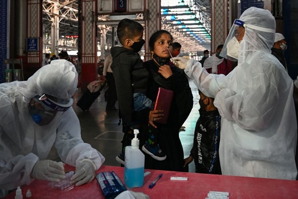 bir saglik calisani hindistan mumbai bir tren istasyonunda hizli test icin bir yolcudan ornek aliyo